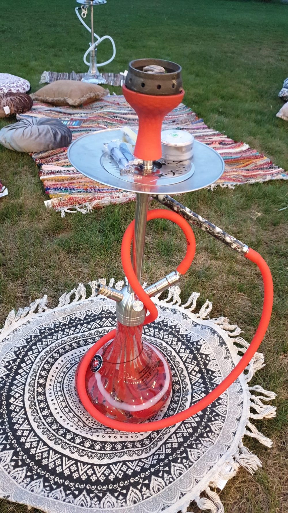 Narghilea roșie pe covor, în aer liber